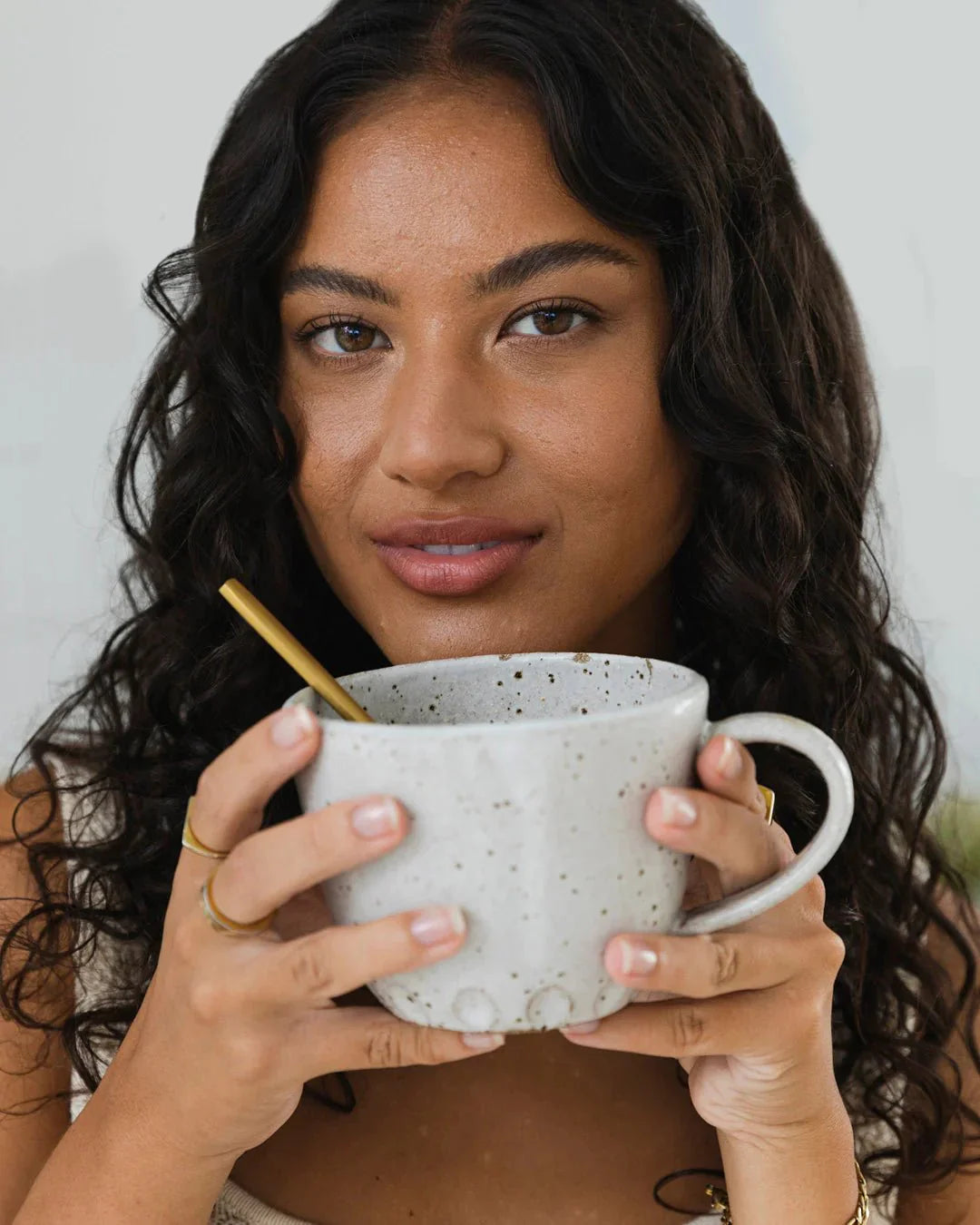 Woman holding a speckled ceramic mug with golden spoon enjoying Beef Bone Broth Concentrate - Natural - 250g beverage