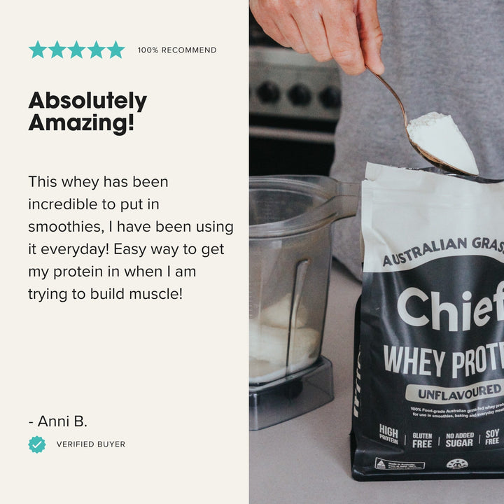 Hand scooping Chief Grass-fed Whey Protein Powder - Unflavoured - 900g bag next to blender in kitchen setting