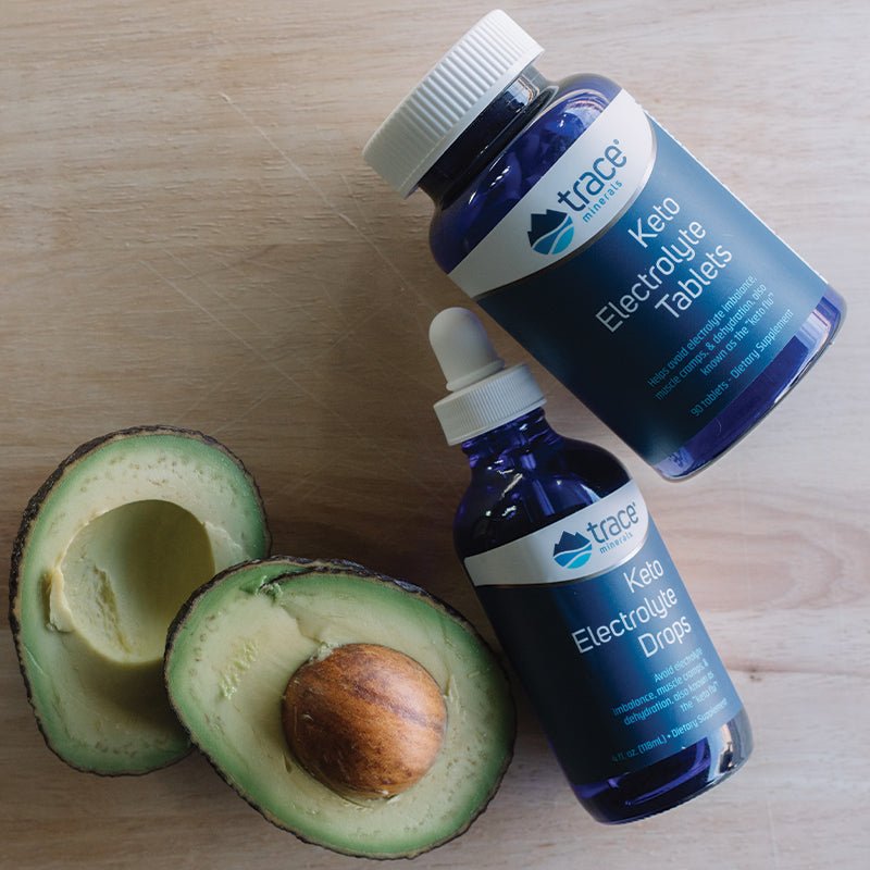 Keto Electrolyte Tablets - 90 Tablets bottle by Trace Minerals next to Keto Electrolyte Drops and sliced avocado on wood
