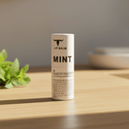Mint Lip Balm - 7g by Bare Bones Beauty displayed on wooden surface with fresh mint leaves nearby.