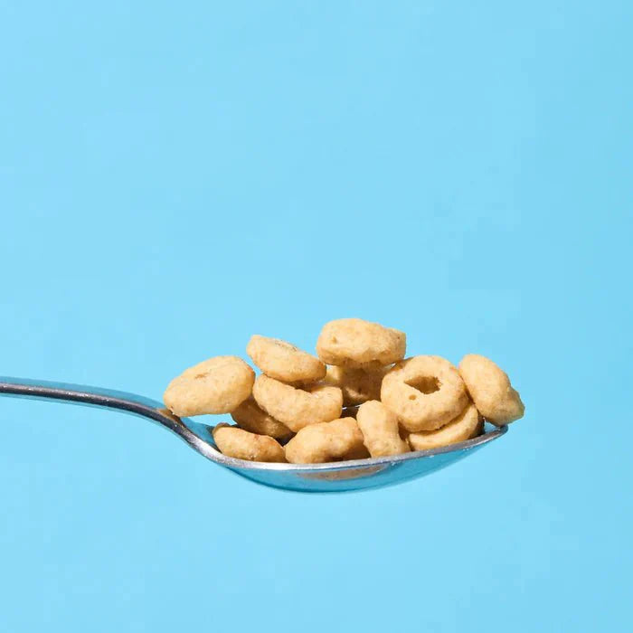 Close-up of a spoon holding Love Low Carb Protein Cereal - Cinnamon Flavour - 250g by Low Carb Emporium on a blue background