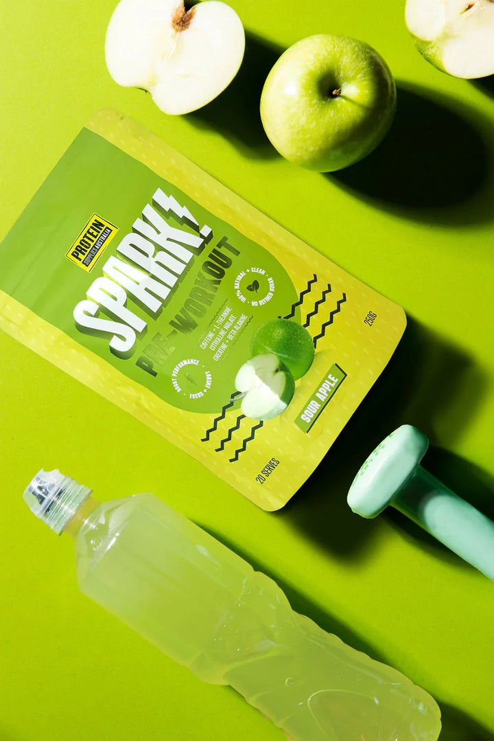 Spark Pre-workout - Sour Apple - 250g with green apple, dumbbell, and water bottle on green background
